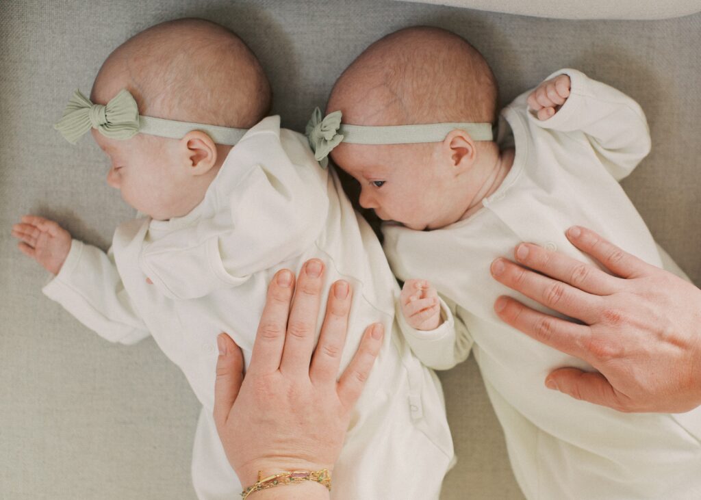 parents laying their hands on their newborn twins